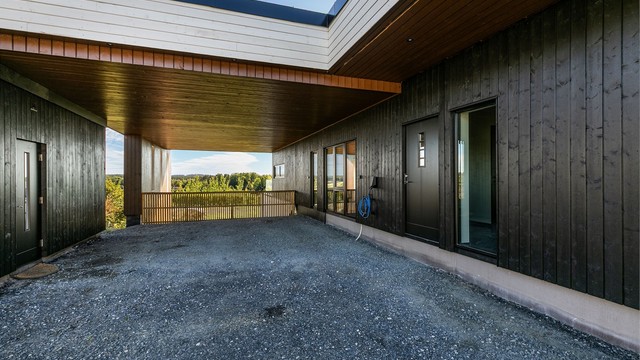 Yttertakets utstikk danner et skjermende overbygg rundt hjørnet mellom carporten og hoveddelens inngangsparti.