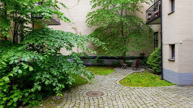 Tomten er opparbeidet med brostein og beplantning.