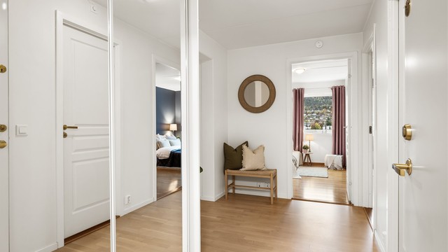 Dørcallinganlegg med åpnerfunksjon og plassbygget skyvedørsgarderobe med speilfronter i entré.