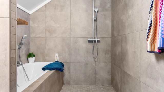 Baderommet har flislagte overflater på gulv og vegger, og takvindu som gir ekstra lys.