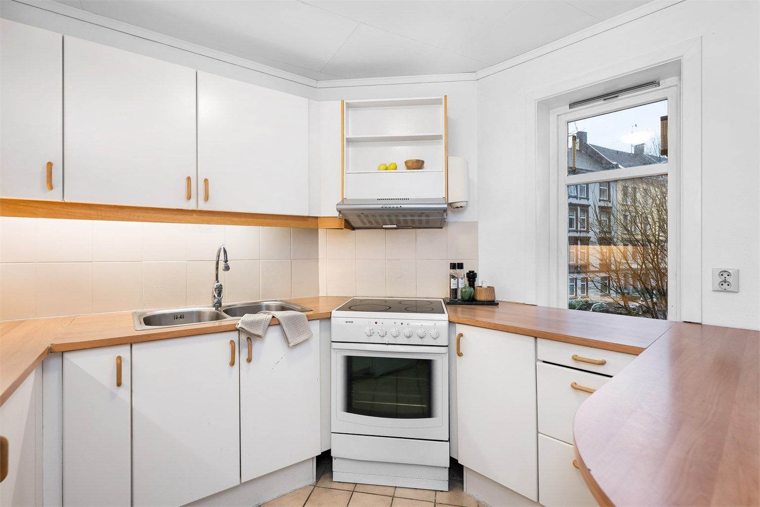 Kjøkkenet er fra ukjent årstall med glatte fronter og benkeplate av laminat. Mellom kjøkkenbenk og overskap er det fliser. 