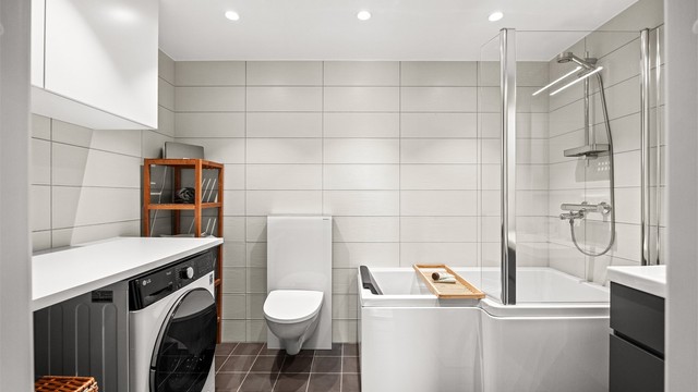 Hovedbadet er flislagt og utstyrt med badekar, vegghengt toalett og opplegg for vaskemaskin.