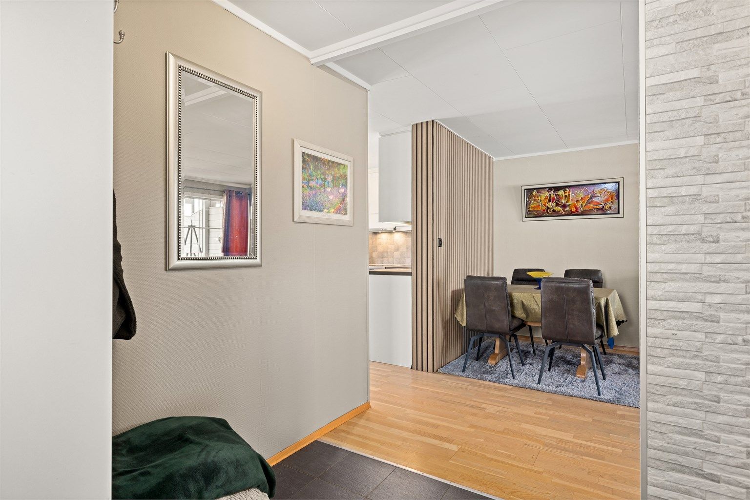 Fra entreen åpner boligen seg opp mot stuen, som har en dekorativ spilevegg.