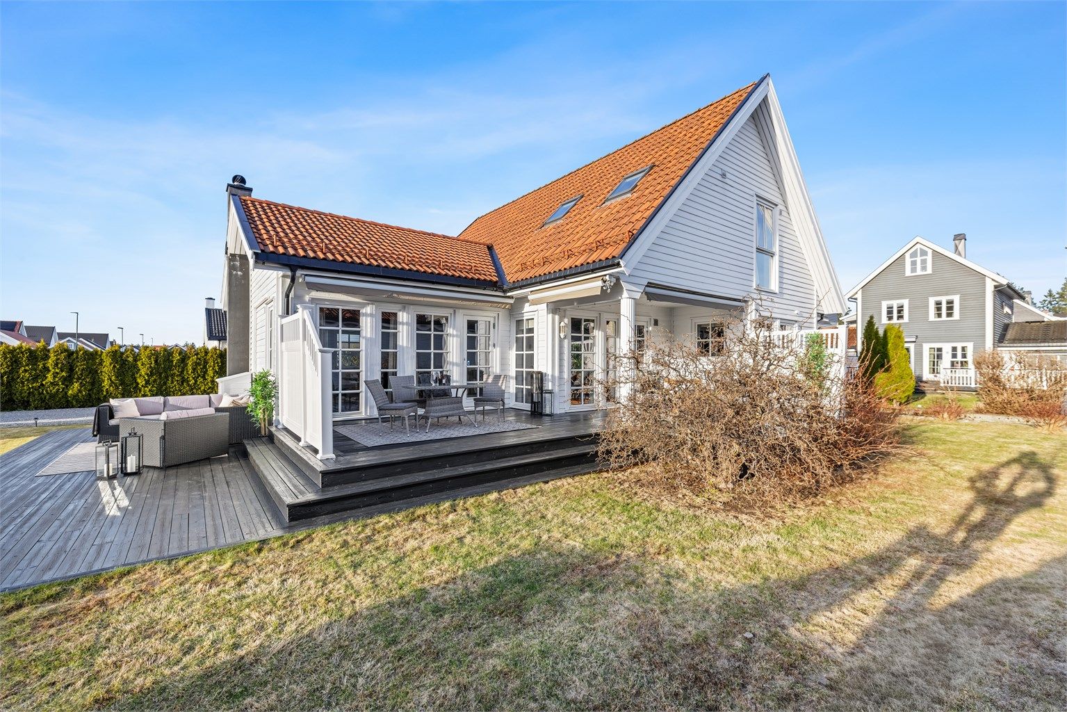 Oversiktsbilde av eiendommen med den store terrassen og hagen.