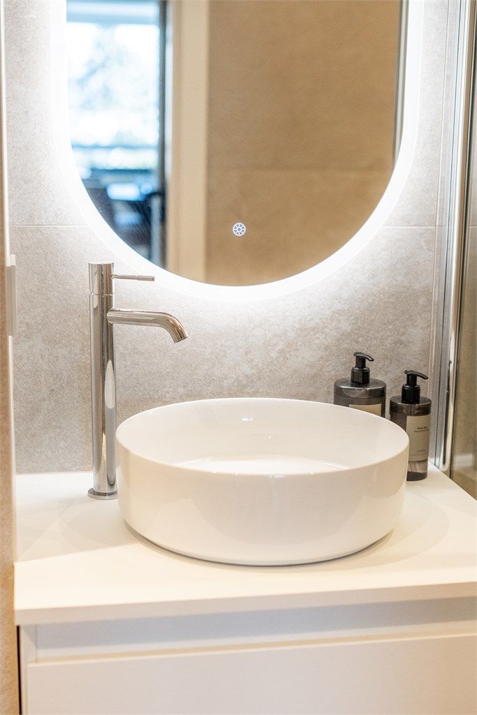 Servantskap med ovenpåliggende servant og speil med integrert belysning og forskjellige fargetoner.