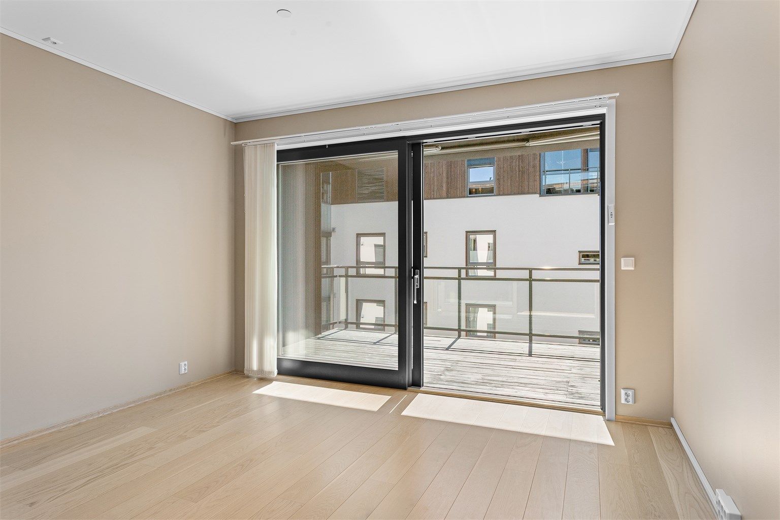 Fra stuen er det direkte utgang til balkongen gjennom en stor skyvedør i tre som slipper inn rikelig med dagslys.