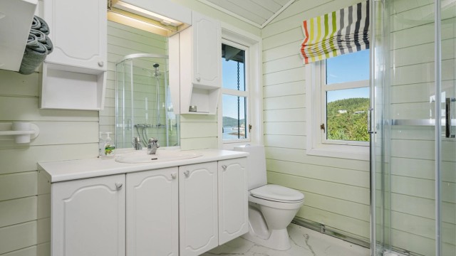 Badet er pent innredet med servantskap med overskap og speil med lys, toalett og dusjkabinett.