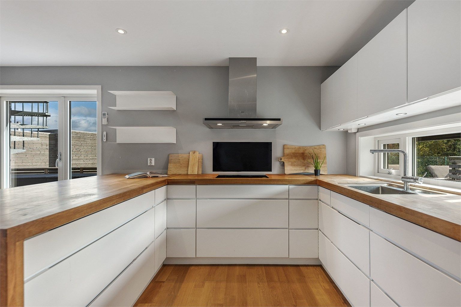 Kjøkkeninnredning fra Kvik i en arbeidsvennlig U-form med slette fronter og integrerte gripefelt.