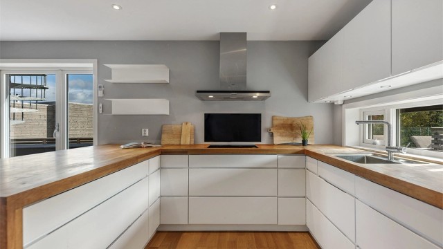 Kjøkkeninnredning fra Kvik i en arbeidsvennlig U-form med slette fronter og integrerte gripefelt.