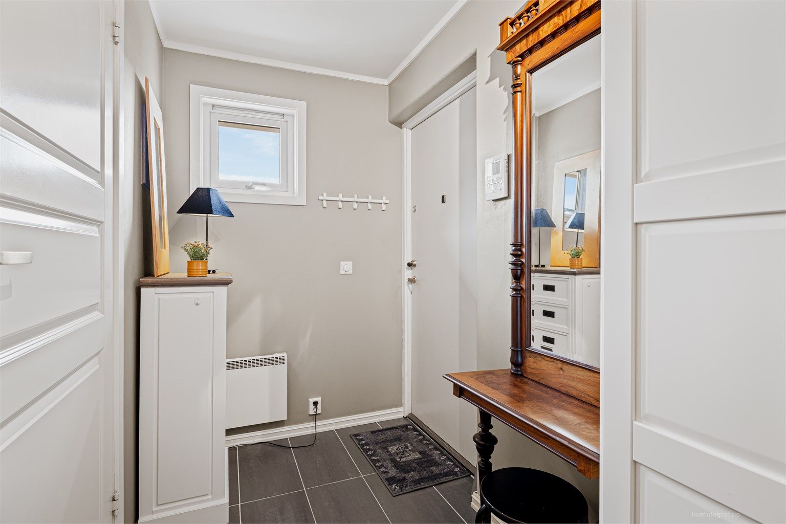 Entréen har flislagt gulv og slett dør med kikkehull samt sikkerhetslås.