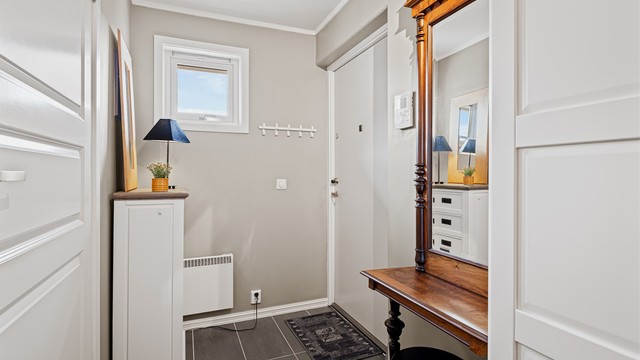 Entréen har flislagt gulv og slett dør med kikkehull samt sikkerhetslås.