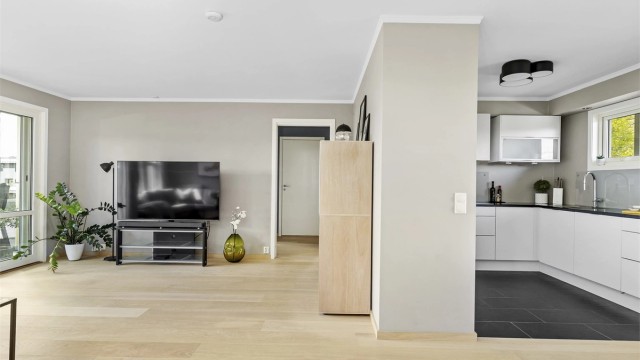 Stuen har en delvis åpen løsning mot kjøkkenet, noe som skaper en god flyt mellom sonene.