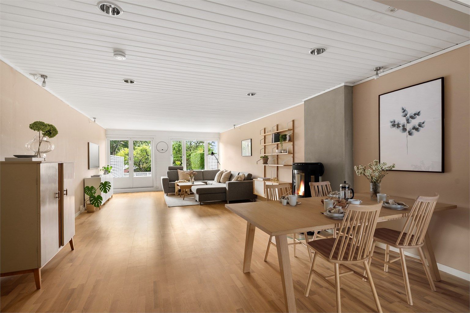 Store vindusflater vendt mot uteplass gir fint grønt utsyn fra hele rommet.