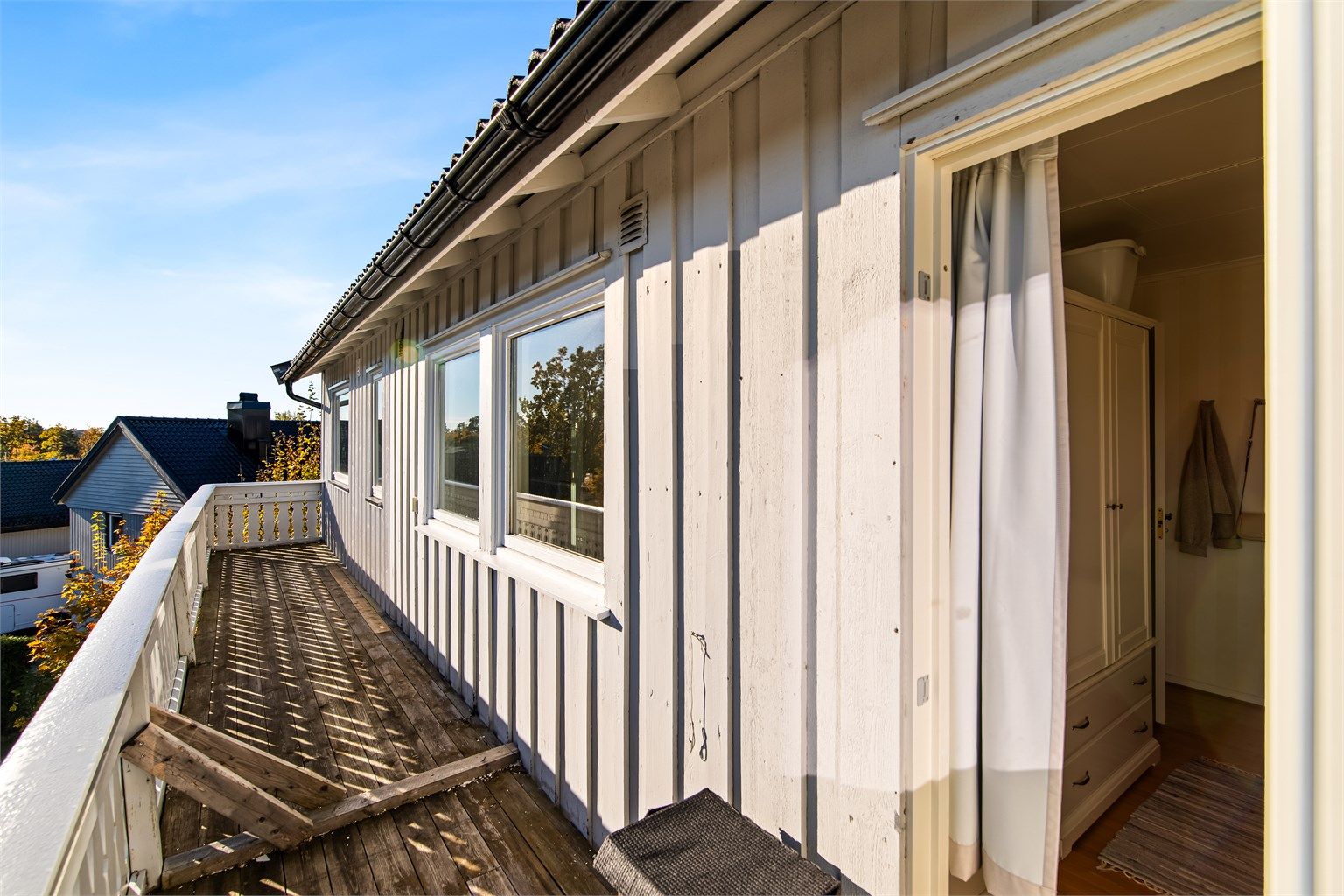 Balkong i trekonstruksjon langs boligens fasade i 1. etasje.