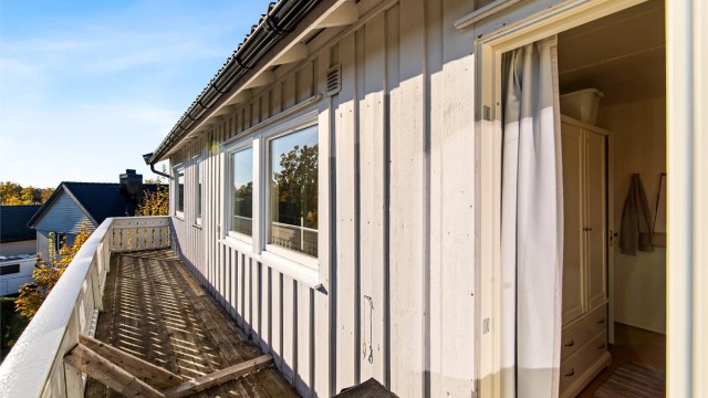 Balkong i trekonstruksjon langs boligens fasade i 1. etasje.