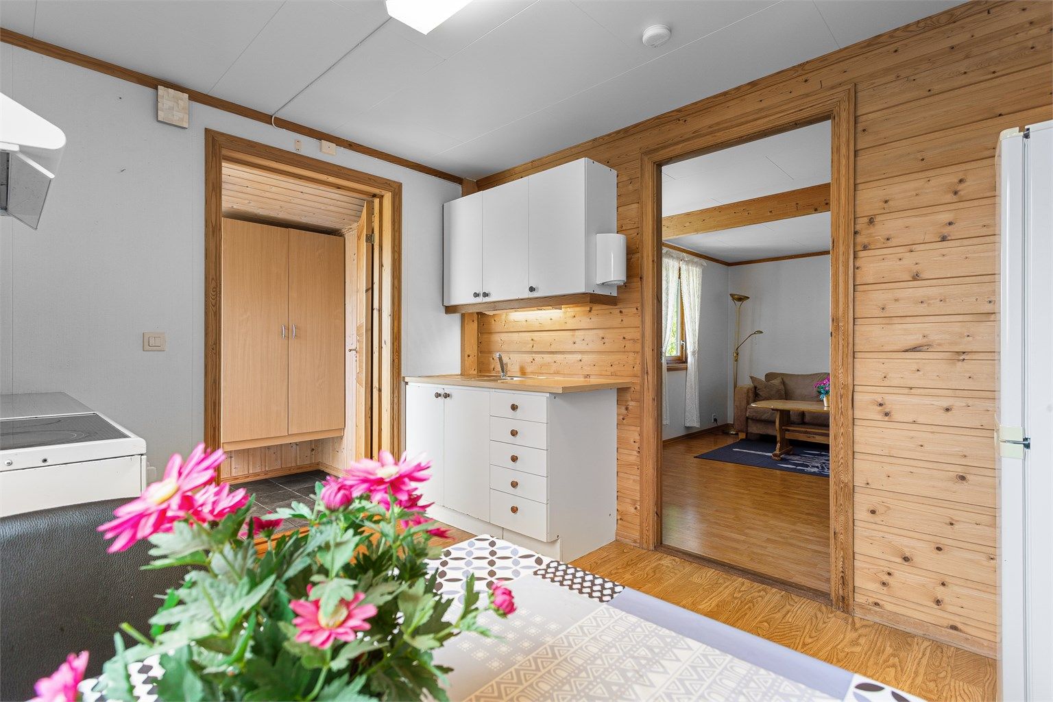 Kjøkken med innredning med slette fronter, benkeplater med laminerte overflate og nedfelt oppvaskkum. Plass til frittstående kjøleskap og komfyr. Ventilator under overskap.