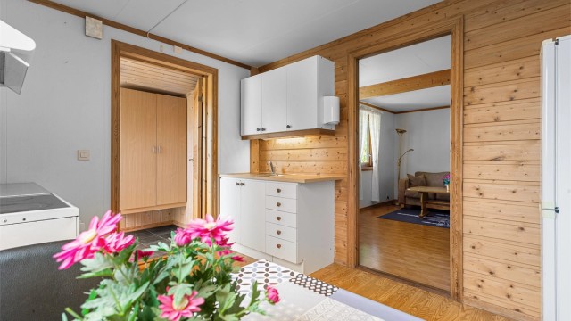 Kjøkken med innredning med slette fronter, benkeplater med laminerte overflate og nedfelt oppvaskkum. Plass til frittstående kjøleskap og komfyr. Ventilator under overskap.