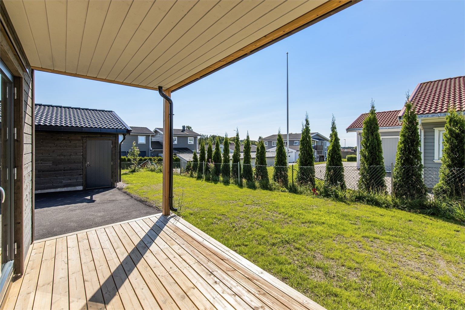 Hagen er plensatt. Overbygget terrasse og hekk mot nabo