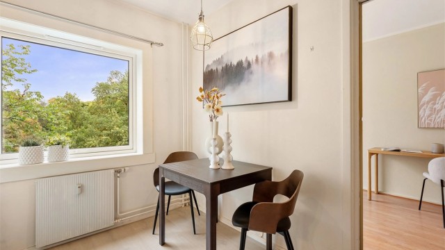 Spiseplass på kjøkkenet med utsikt mot grønne omgivelser.