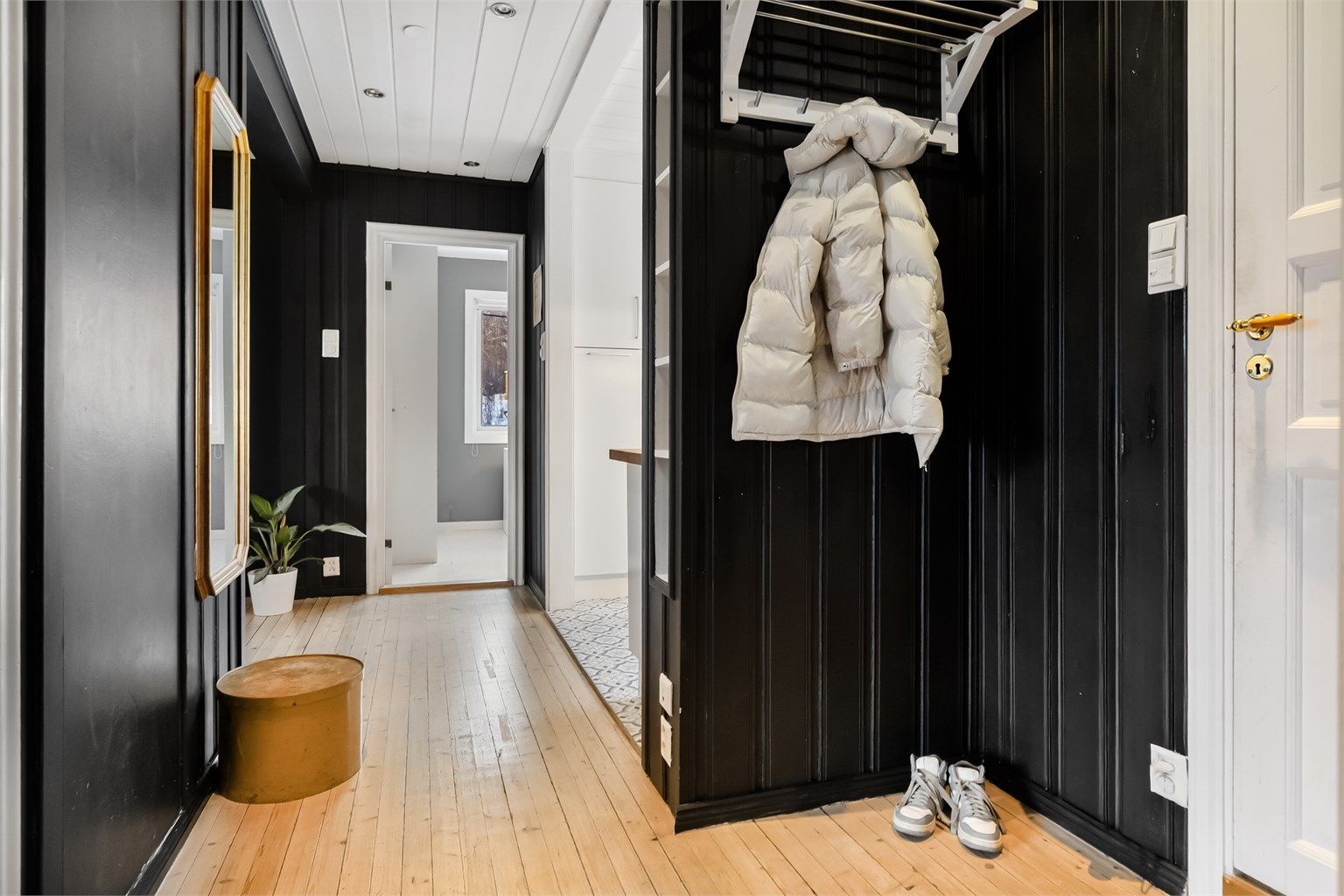 Fra felles trappegang kommer man inn i en entré med panelkledde vegger og tregulv.