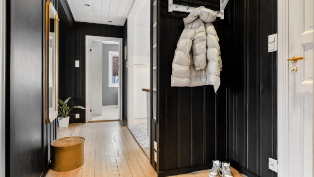 Fra felles trappegang kommer man inn i en entré med panelkledde vegger og tregulv.