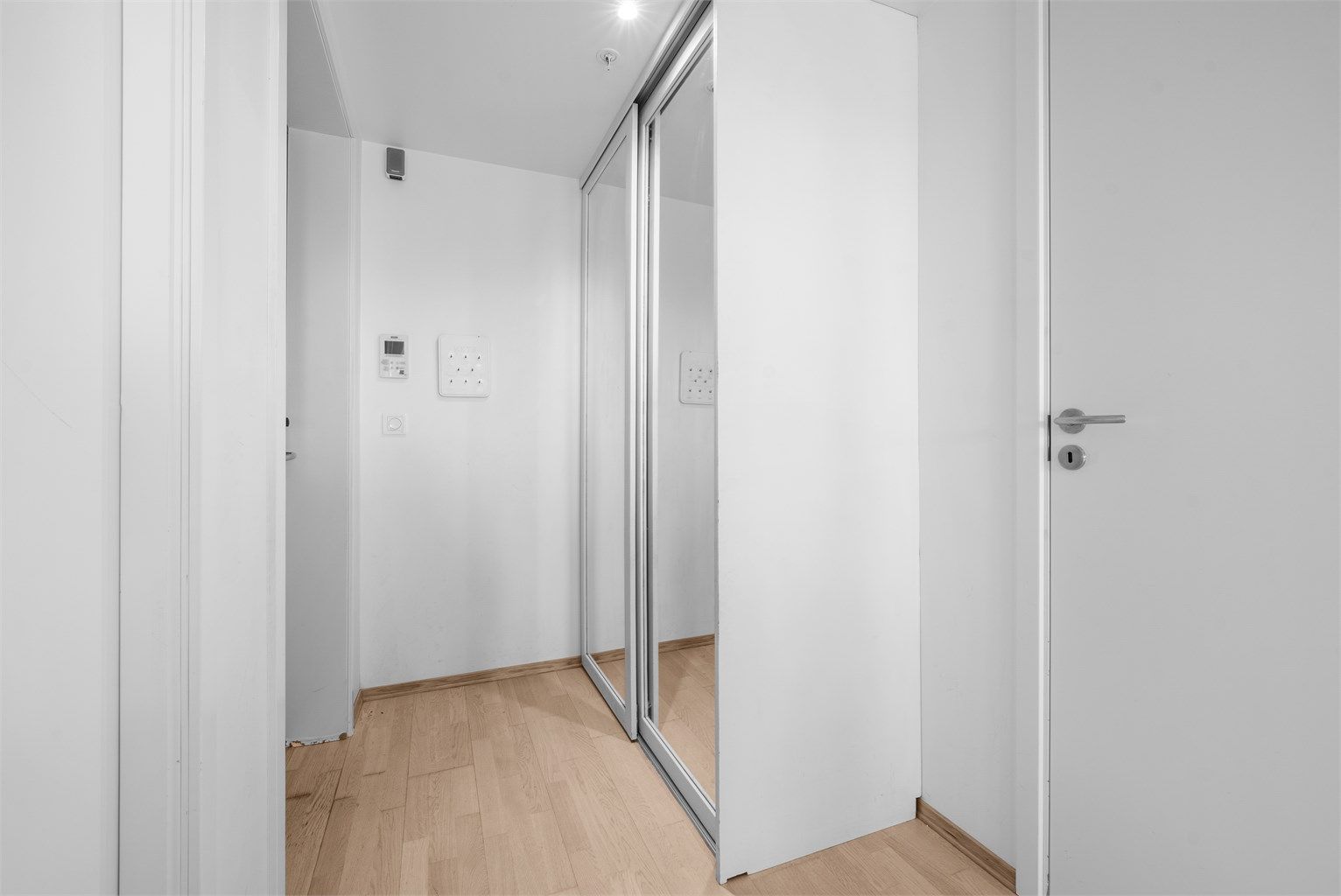 Entréen har trestavs parkett på gulv og en romslig skyvedørsgarderobe med speilfronter, montert i 2018.