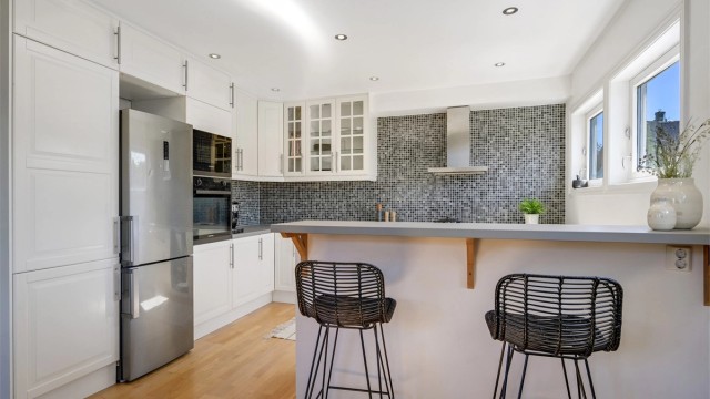 Kjøkkenet har innredning med profilerte fronter. Benkeplaten er av heltre som er malt i senere tid. Det er avsatt plass til frittstående kjøl/fryseskap og oppvaskmaskin i nisjer. Av integrerte hvitevarer er det platetopp, vinskap, micro og stekeovn.