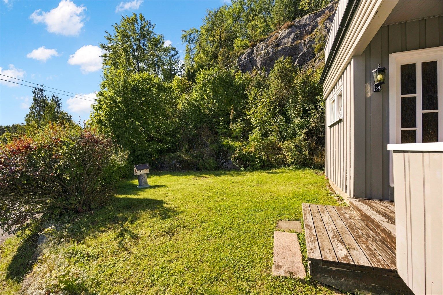 Eiendommen grenser mot et naturlig fjellparti og frodig skogsterreng.