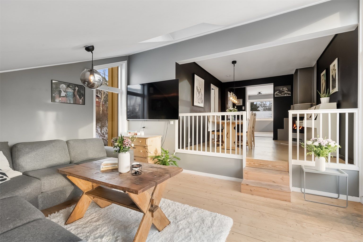 Stuen er et lyst og romslig oppholdsrom med tregulv og flere vinduer.