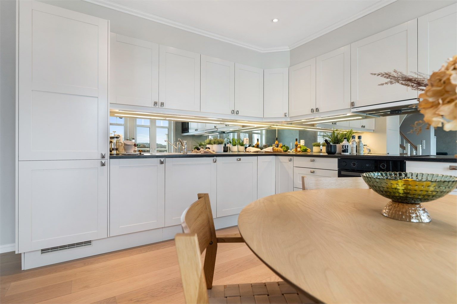 Kjøkkenet har innredning med profilerte fronter og benkeplate av laminat. Speil mellom benk og overskap, reflekterer lyset og skaper en romslig og elegant finish