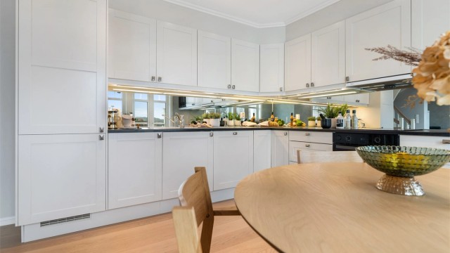 Kjøkkenet har innredning med profilerte fronter og benkeplate av laminat. Speil mellom benk og overskap, reflekterer lyset og skaper en romslig og elegant finish