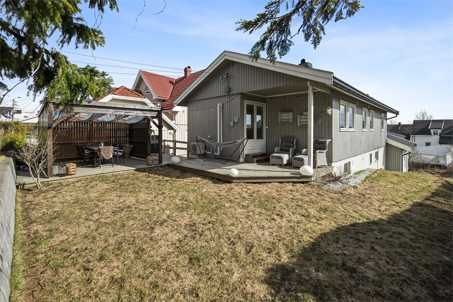 Hagen er opparbeidet med plenarealer og en stor treterrasse som strekker seg langs husveggen.