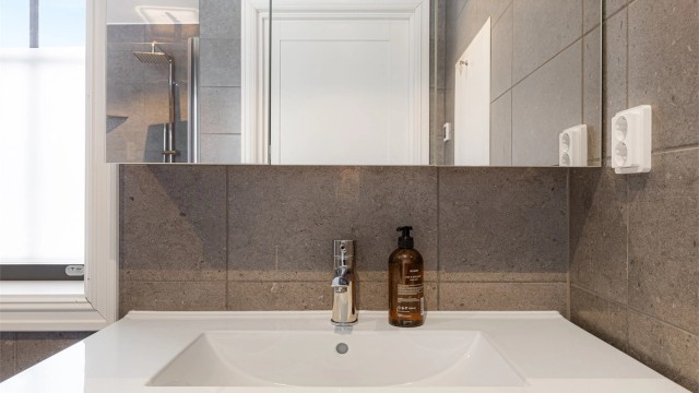 Et stort speilskap med integrert belysning gir godt lys og ekstra oppbevaring.