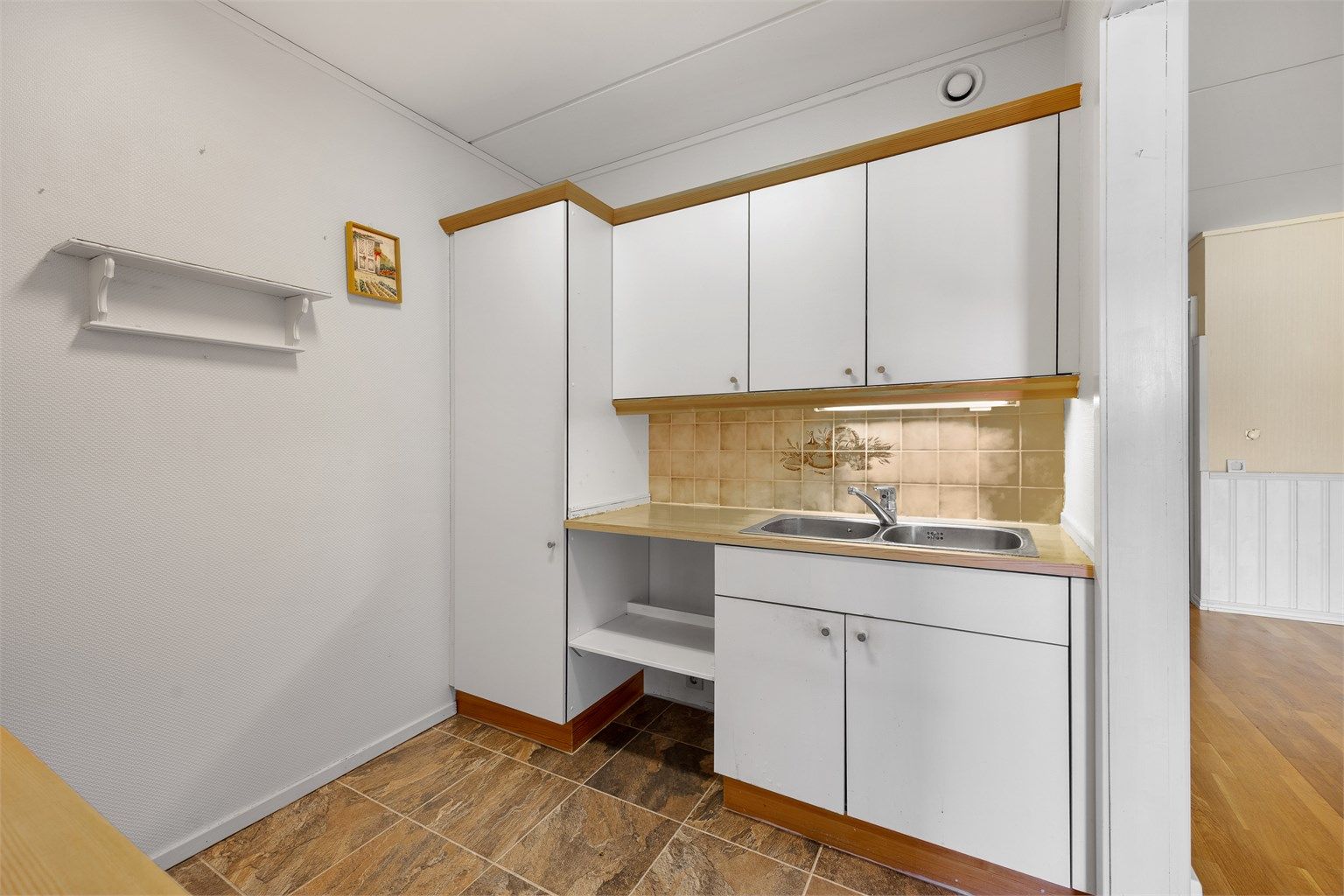 Kjøkkeninnredning fra byggeåret med laminert benkeplate og fliser over benken.