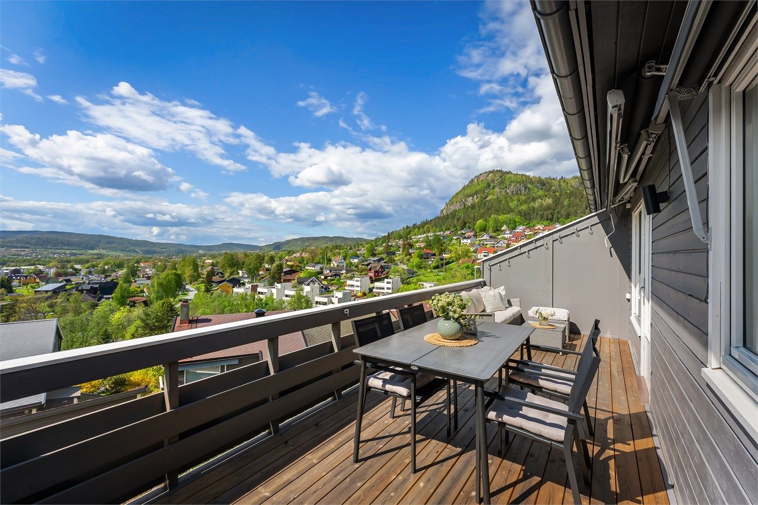Balkongen har rekkverk av tre og gulv belagt med terrassebord.