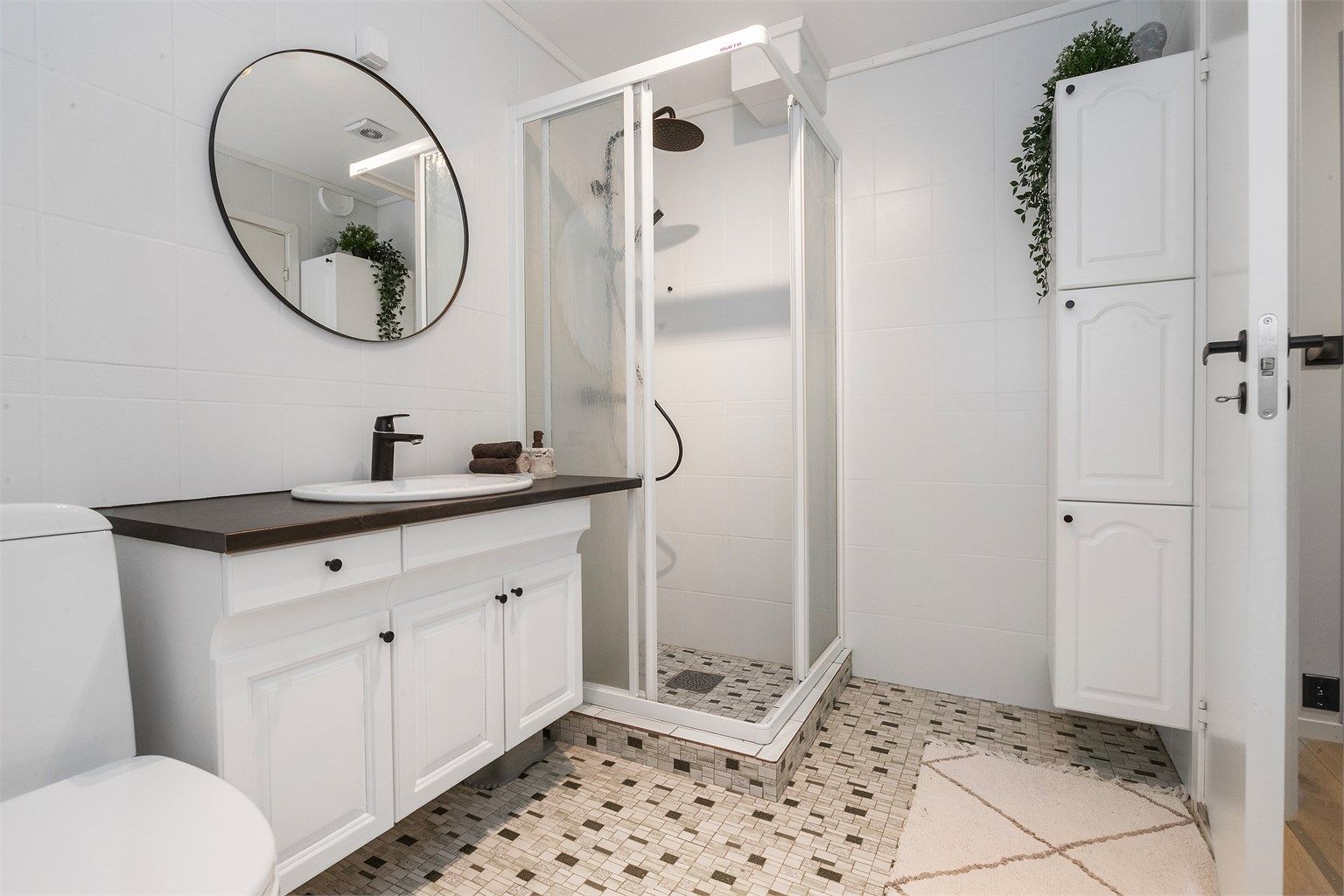 Bad med varmekabler, utstyrt med dusjkabinett og servant med underskap.