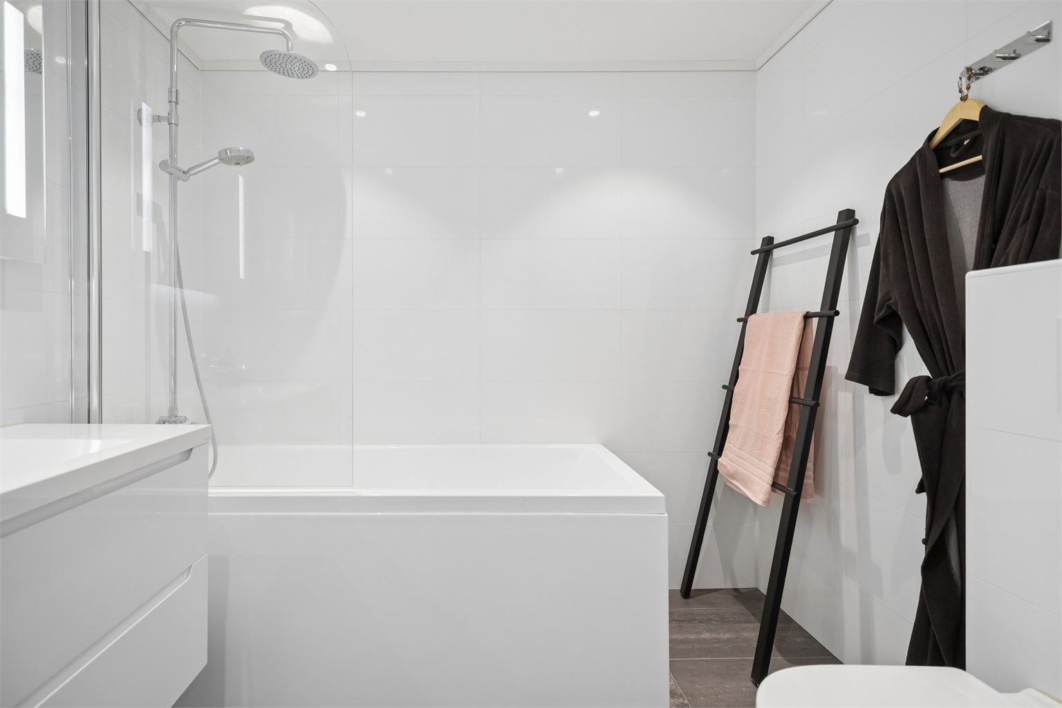 Badet i 2.etg er flislagt og har gulvvarme, vegghengt toalett, servantskap, speil med lys samt badekar.