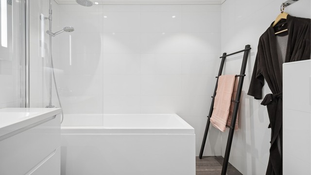 Badet i 2.etg er flislagt og har gulvvarme, vegghengt toalett, servantskap, speil med lys samt badekar.
