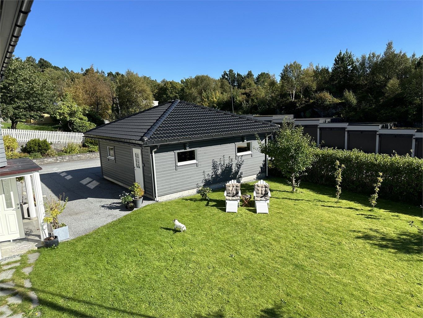 Skjermet hage med plen og beplantinger - bilde tatt fra terrassen av selger sommerstid
