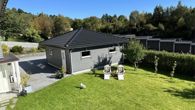 Skjermet hage med plen og beplantinger - bilde tatt fra terrassen av selger sommerstid