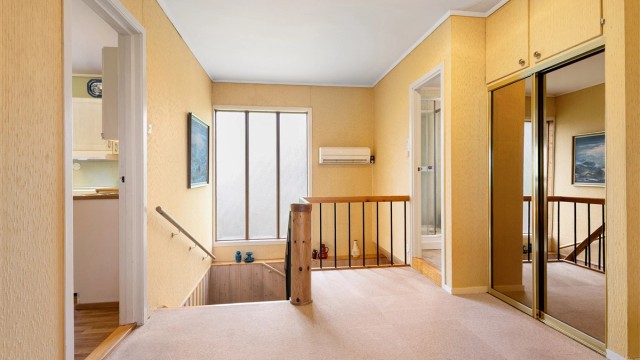 Fra toppen av trappen ser man ned mot underetasjen. En luft-til-luft varmepumpe er montert i hallen.