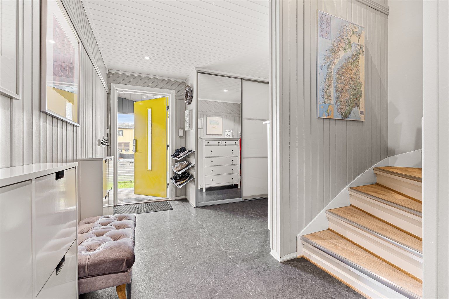 Entréen har flislagt gulv med varmekabler og en romslig skyvedørsgarderobe med speilfronter.