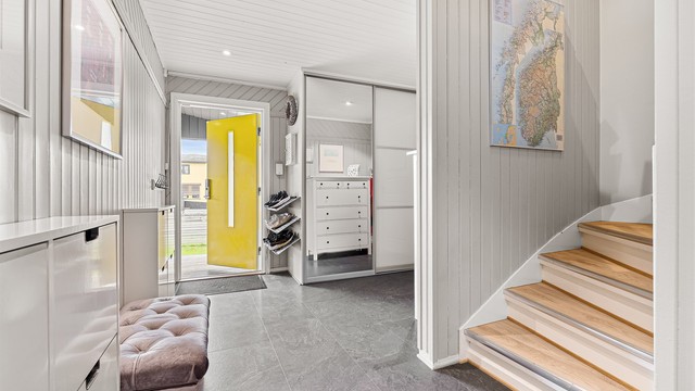 Entréen har flislagt gulv med varmekabler og en romslig skyvedørsgarderobe med speilfronter.