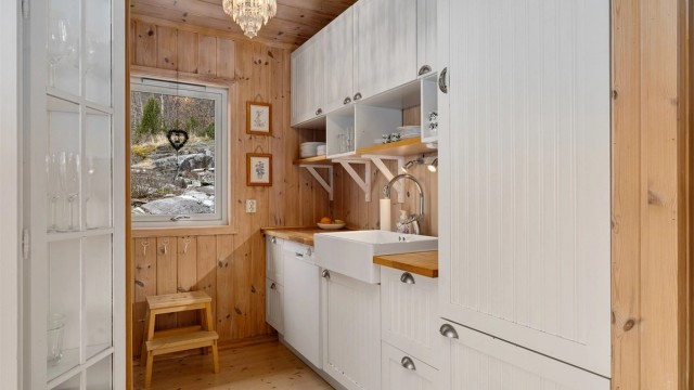 PRAKTISK OG PENT: Det hvitmalte kjøkkenet fra R.o.o.m. bidrar til å veie opp for mye treverk i hytta for øvrig. Men benkeplaten er utført i heltre.