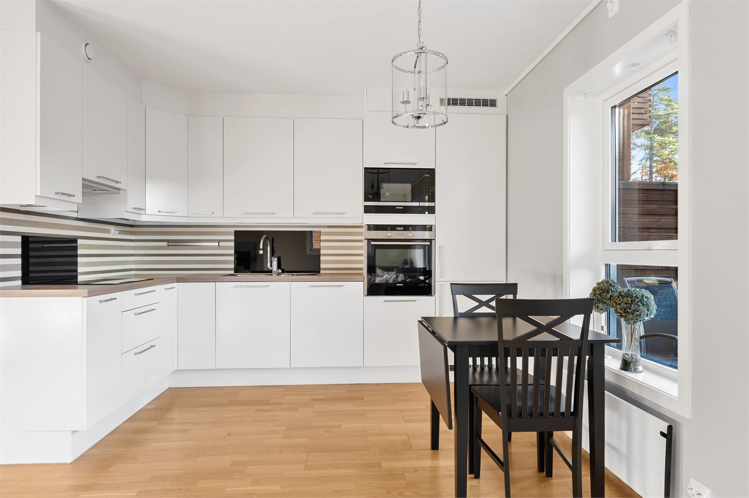 Flott velholdt kjøkken med takhøye skap og integrerte hvitevarer