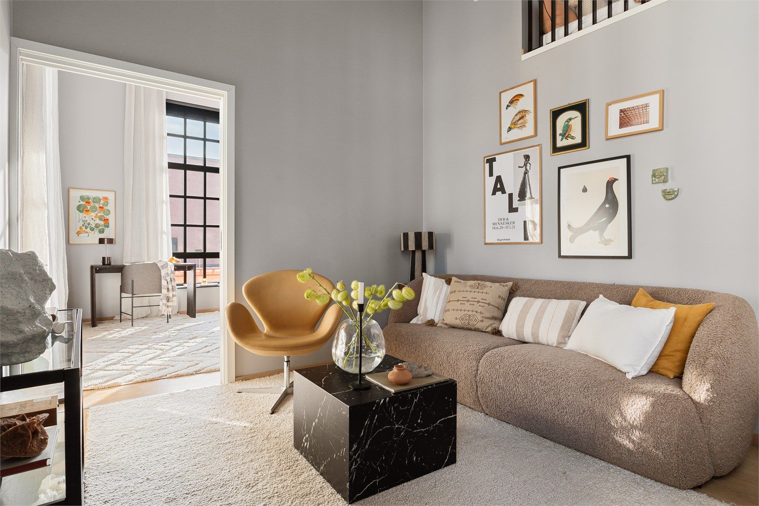 Stuen fremstår som lys og luftig med imponerende takhøyde og store, karakteristiske fabrikkvinduer som slipper inn rikelig med naturlig lys.