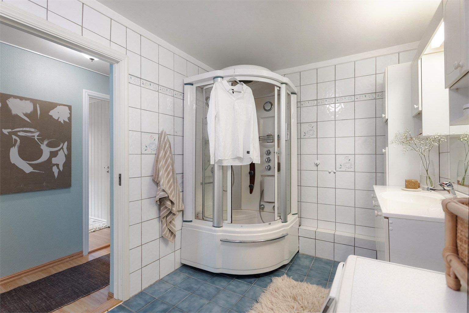 Flislagt bad med dusjkabinett og praktisk opplegg for vaskemaskin.