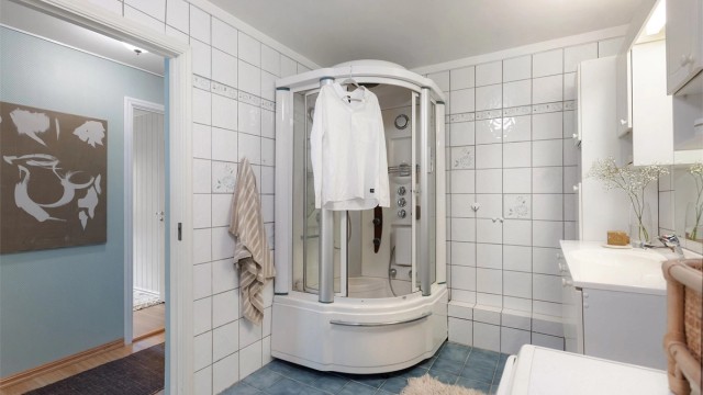 Flislagt bad med dusjkabinett og praktisk opplegg for vaskemaskin.