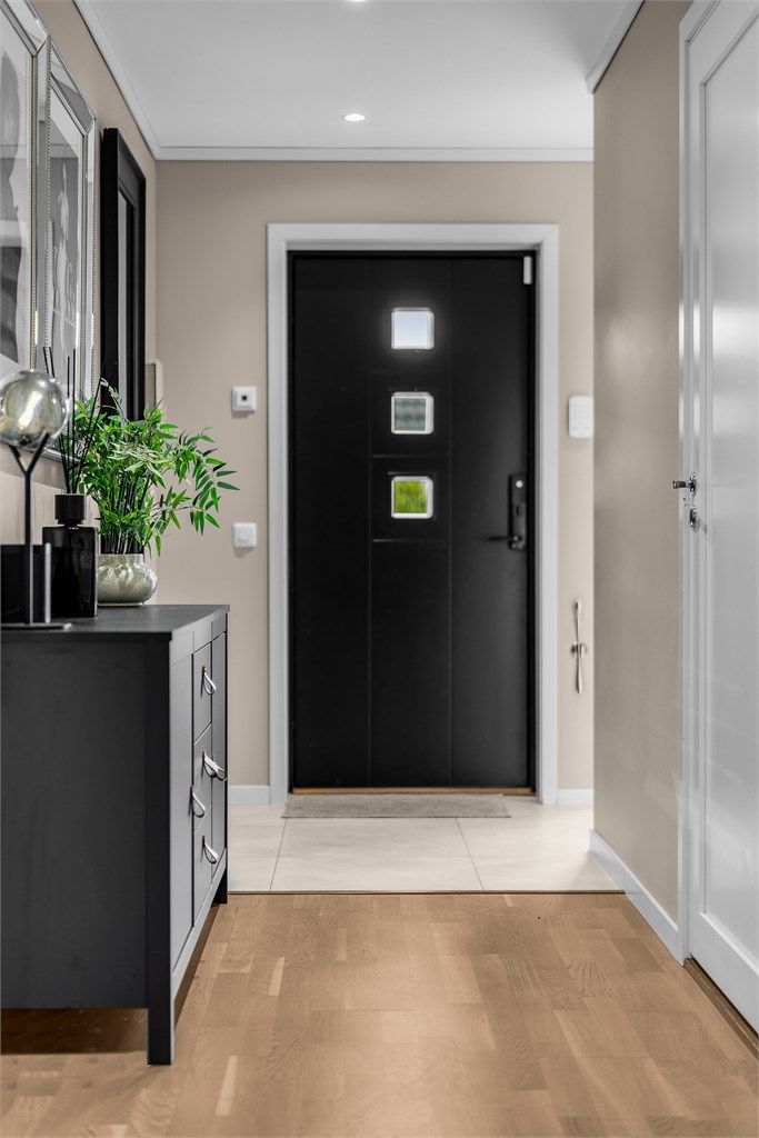 Innbydende entré med flislagt gulv og varmekabler. Her er det godt med plass for oppbevaring av yttertøy.