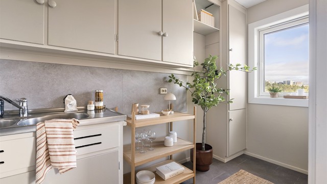 Innredningen har malte fronter og heldekkende benkebeslag med skylle- og oppvaskkum.
